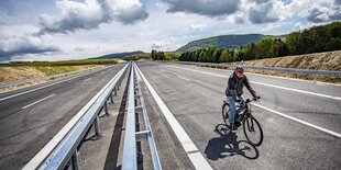 Ein Fahrradfahrer auf einer neuenvierspurigen Straße