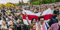 Eine Menschenmenge, jemand hält eine rot-weiße Fahne