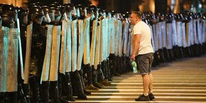 Ein Mann steht vor einer Reihe von uniformierten Polizistentsen