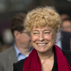 Gesine Schwan, eine alte Frau mit blonden, kurzen Locken. Sie lächelt mit offenem Mund. Sie trägt einen roten Tuchschal und ein Schwarzes Oberteil.