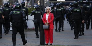 Frau im roten Kostüm inmitten von Polizisten