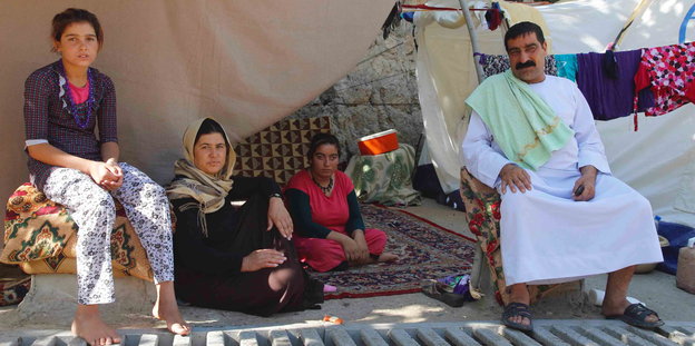 Eine jesidische Flüchtlingsfamilie sitzt vor einem Zelt