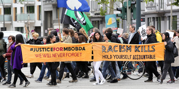 Demonstrierende halten ein Banner in der Hand, darauf fordern sie Gerechtigkeit