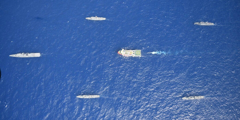 Aus der Vogelperspektive fotografiert: Ein großes Schiff umringt von mehreren kleinen.