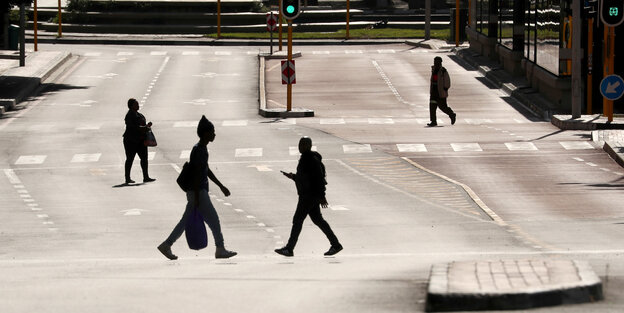Vier Personen laufen über eine Straße