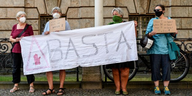 Vier Frauen protestieren mit einem Basta-Transparent vor dem Amtsgericht Tiergarten
