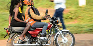 Auf einem Motorrad sitzt ein Mann mit Helm, auf dem Rücksitz eine Frau ohne Helm.