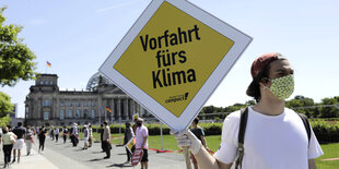 Ein Mann hält bei Protesten ein Schild hoch, auf dem Vorfahrt fürs Klima steht.