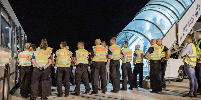 Ein Mann wird von Polizisten durch eine Gangway geführt