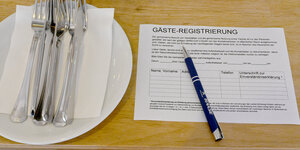 Ein Zettel für die Gäste-Regstrierung liegt in einem Restaurant auf einem Tisch.
