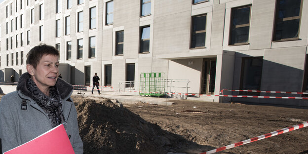 Die Berliner Sozialsenatorin Elke Breitenbach von der Linkspartei steht vor einer neu eröffneten Unterkunft für Geflüchtete in Berlin. Das Bild stammt aus dem Jahr 2017. Die Unterkunft ist ein schmuckloser mehrgeschossiger Bau aus hellem Beton.