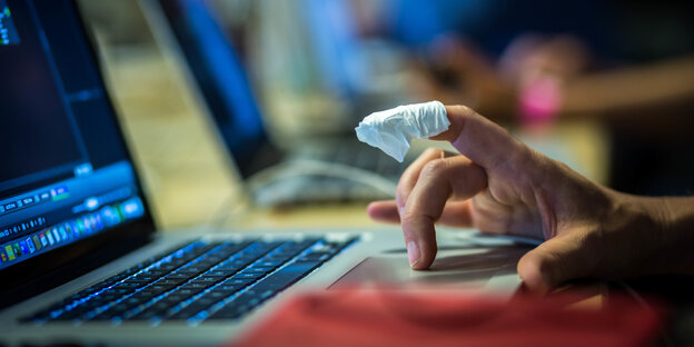 Ein Computer mit einer tippenden Hand, der Zeigefinger ist bandagiert