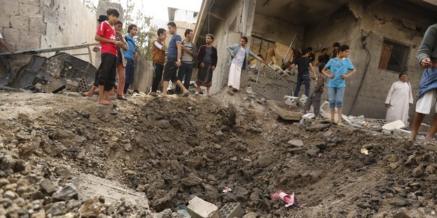 Bewohner der Haupstadt Sanaa vor einem Einschlagloch