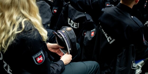 Eine junge Polizeianwärterin hält ihre Polizeimütze in der Hand