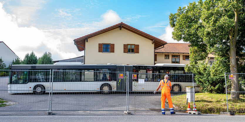 Ein Mann stellt Absperrgitter vor einem Bauernhof auf