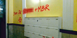 Eine Hauswand mit Briefkästen: Mit roter Farbe ist darüber gesprüht: "9mm für xxx (geschwärzt) + MBR"