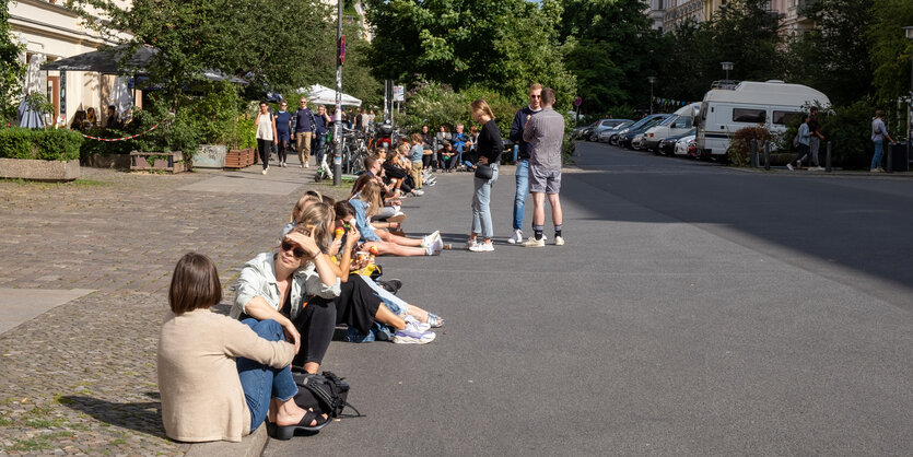 Junge Menschen sitzen auf einer Bordsteinkante