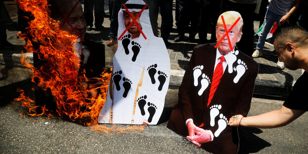 DemonstrantInnen zündne Bilder von Netanjahu, Prinz Mohammed bin Zayed al-Nahyan und Trump an.