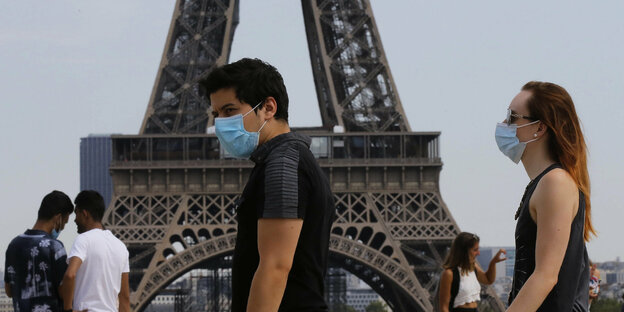 Menschen mit Schutzmasken vor dem Eiffelturm