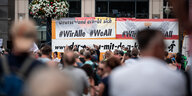 Menschenmenge vor einem Plakat mit der Aufschrift "Wir alle"