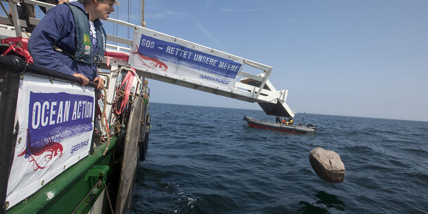 Von einem Schiff der Umweltschutzoirganisation Greenpeace aus wird ein Felsbrocken ins Meer geworfen