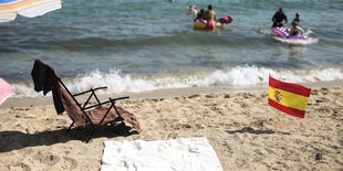 Strand mit Handtuch und spanischer Fahne.