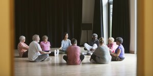 Menschen sitzen zur Meditation im Kreis