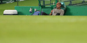 Trainer Pep Guardiola sitzt alleine auf der Bank, in der Hand eine leere Wasserflasche