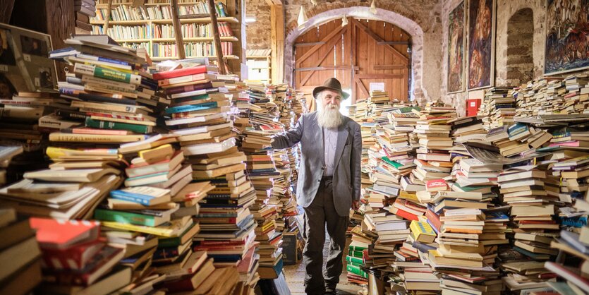 Martin Weskott zwischen hohen Bücherstapeln