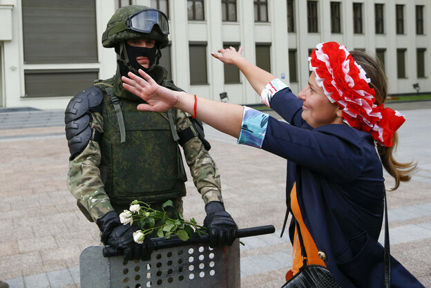 Eine Frau mit rotem Tuch um den Kopf geht mit offenen Armen auf einen Soldaten zu, um ihn zu umarmen
