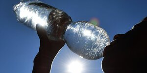 Junge trinkt Wasser aus einer Plastikflasche bei grosser Hitze