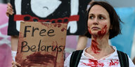 eine Demonstrantin hält ein Schild hoch "Free Belarus" - ihr Gesicht und T-shirt ist symbolisch mit Kunstblut beschmiert