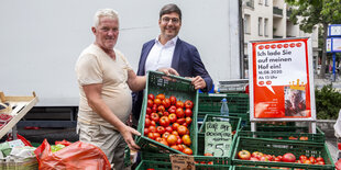 Zwei Männer stehen auf einem Wochenmarkt