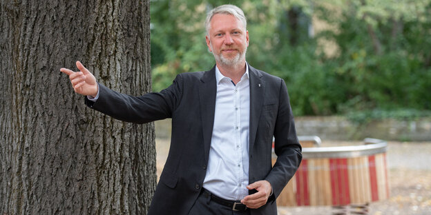 Sebastian Scheel steht neben einem Baum