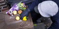Getarnter Mensch an einer Mülltone mit Obst