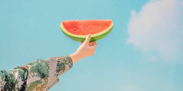 Eine Hand hält ein Stück Wassermelone in den Himmel