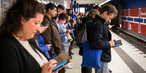 eine Menschengruppe wartet mit Smartphones in der hand in einer Ubahn