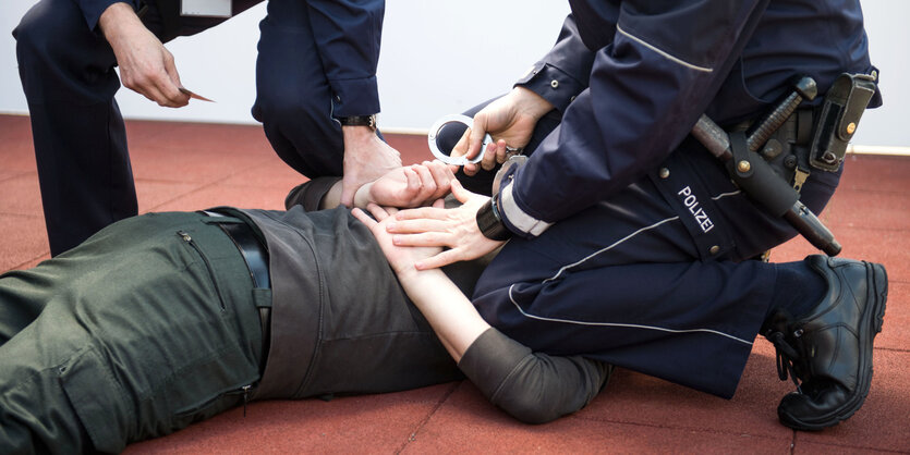 ein Polizist kniet bei einer Übung auf einen Mann