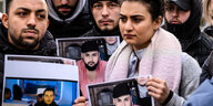 Angehörige halten Fotos von den ermordeten Menschen hoch