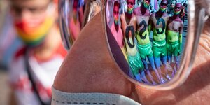 Mensch mit Sonnenbrille in der sich Regenbogenmenschen spiegel