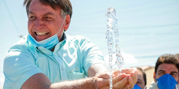 olsonaro spielt an einem Brunnen lächelnd mit dem Wasser
