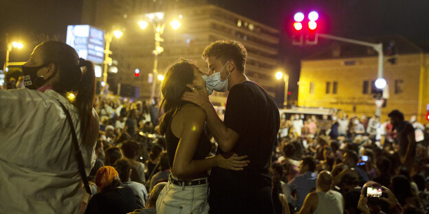 Zwei Menschen mit Mundschutz küssen sich