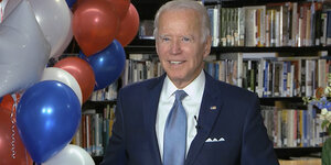 Joe Biden mit Luftballons vor einem Buchregal