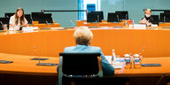 Merkel von hinten sitzt an einem riesigen runden Tisch, in großer Entfernung sitzen Luisa Neubauer (links) und Greta Thunberg (rechts und mit Atemschutzmaske)