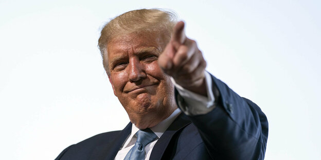 Donald Trump zeigt mit dem Finger in einer Richtung und grinst