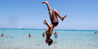 Ein Junge macht einen Salto am Mondello Strand