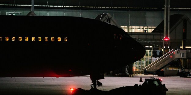 Ein flugzeug steht nachts auf dem Flughafen München, die Fenster der Maschine sind erleuchtet