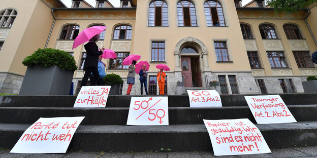 Menschen mit rosa Regenschirmen demonstrieren vor dem Thüringer Verfassungsgerichtshof