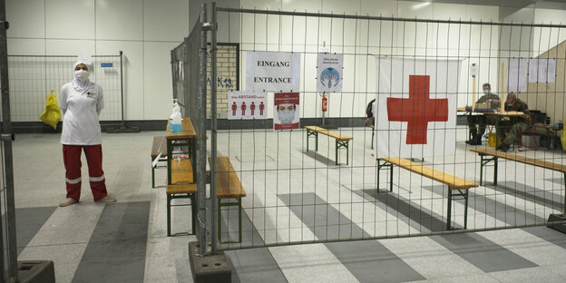 In einem mit Gittern abgesperrten Bereich im Berliner Hauptbahnhof warten Menschen in Schutzkleidung auf Personen, die sich auf Corona testen lassen wollen.