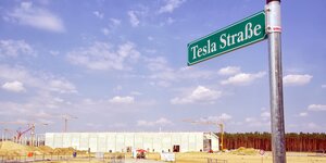 Ein Straßenschild mit der Aufschrift "Tesla Straße" vor der Tesla-Großbaustelle in Brandenburg